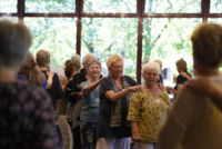 Viele Frauen laufen im Kreis hintereinander. Sie spielen ein Gemeinschaftsspiel.